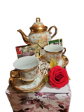 Floral gold-trimmed teapot and two teacups gift set with tea, a candle and a red rose